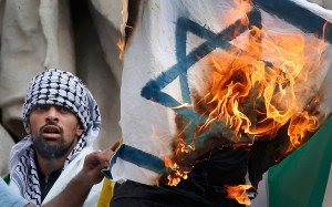 Pro Palestinian protester burns an Israeli flag during banned demonstration in support of Gaza in central Paris